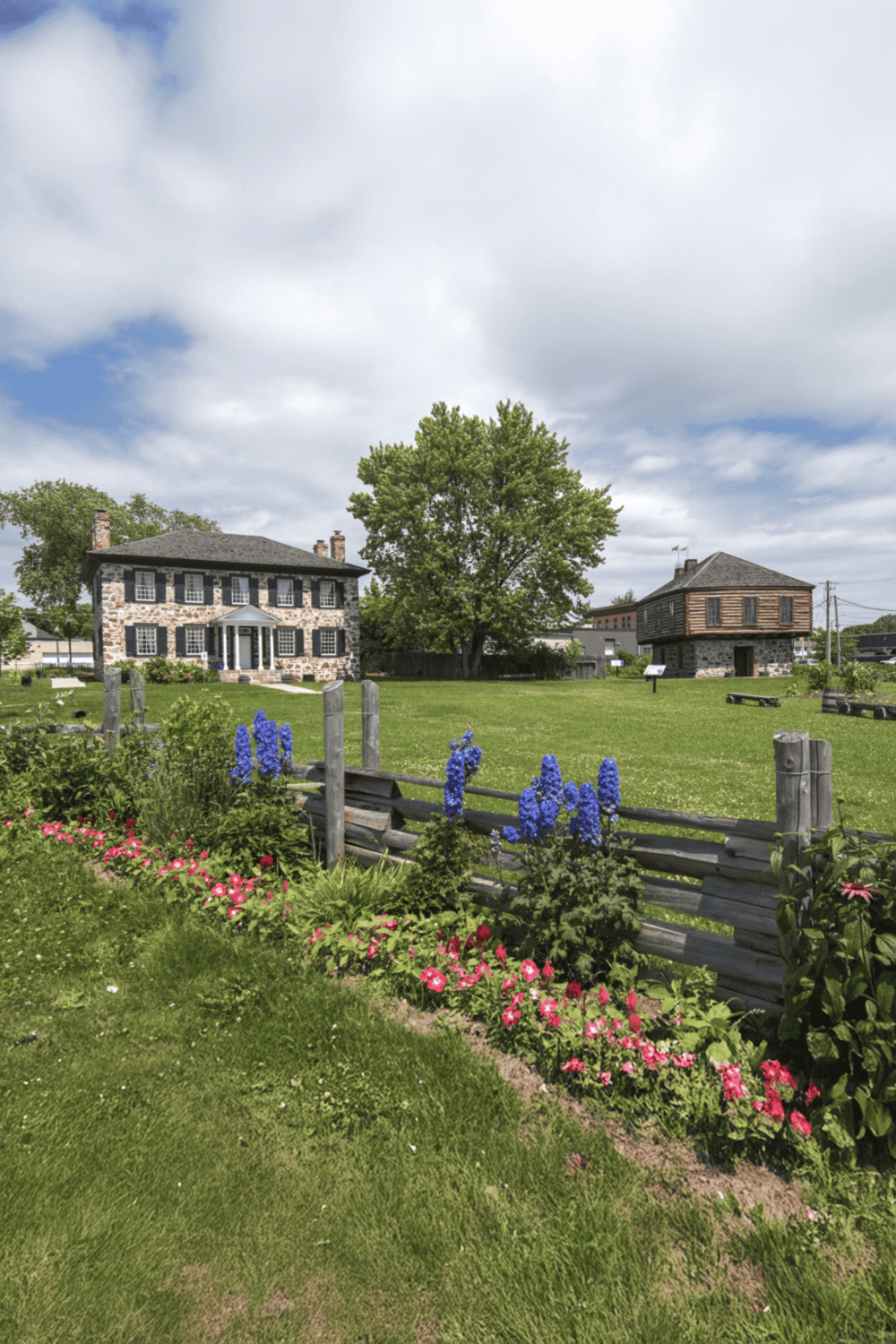Stone historic homes with lush gardens and blue flowers, ideal for history and architecture enthusiasts.