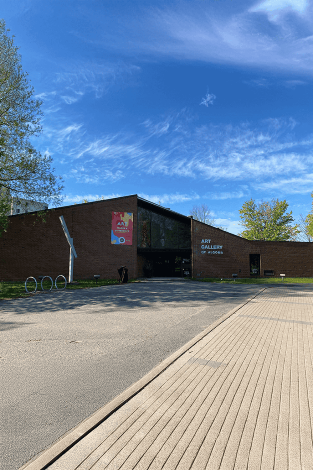 Colorful art gallery building in Algoma under blue sky, surrounded by green trees.