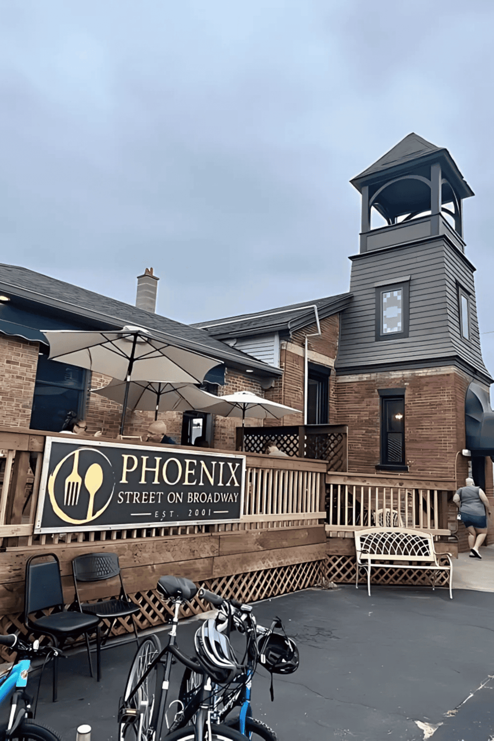 1. Charming brick and gray exterior of Phoenix Street on Broadway with outdoor seating and bicycles.