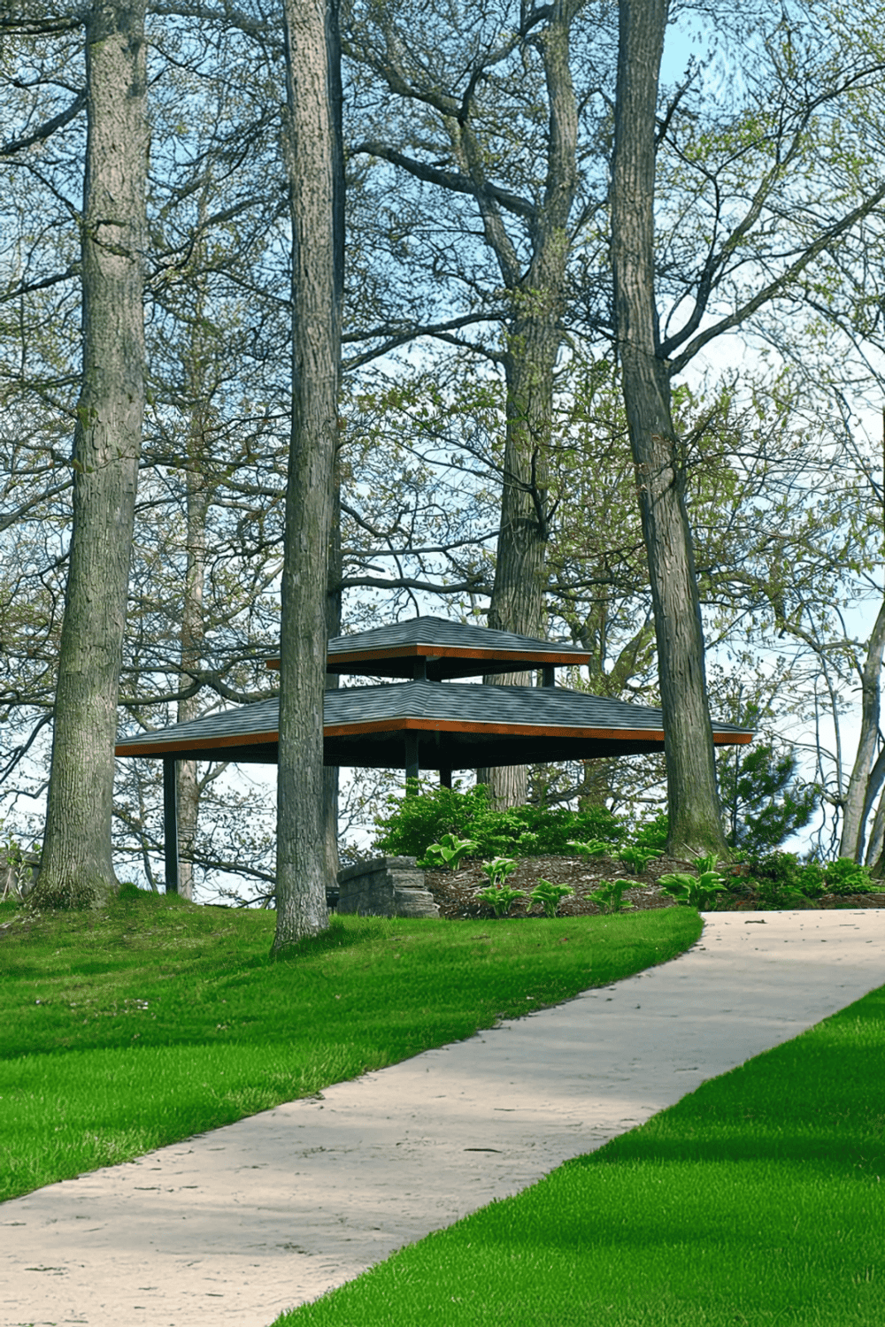 Serene park pavilion with lush greenery and tall trees, perfect for outdoor relaxation and social gatherings.