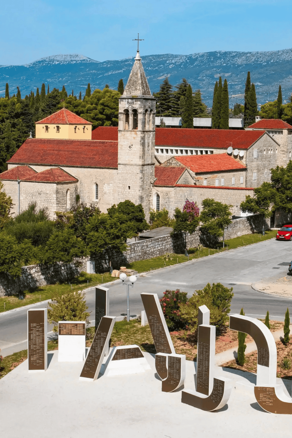 Medieval church and historic architecture in Dubrovnik, Croatia, with scenic mountain backdrop.