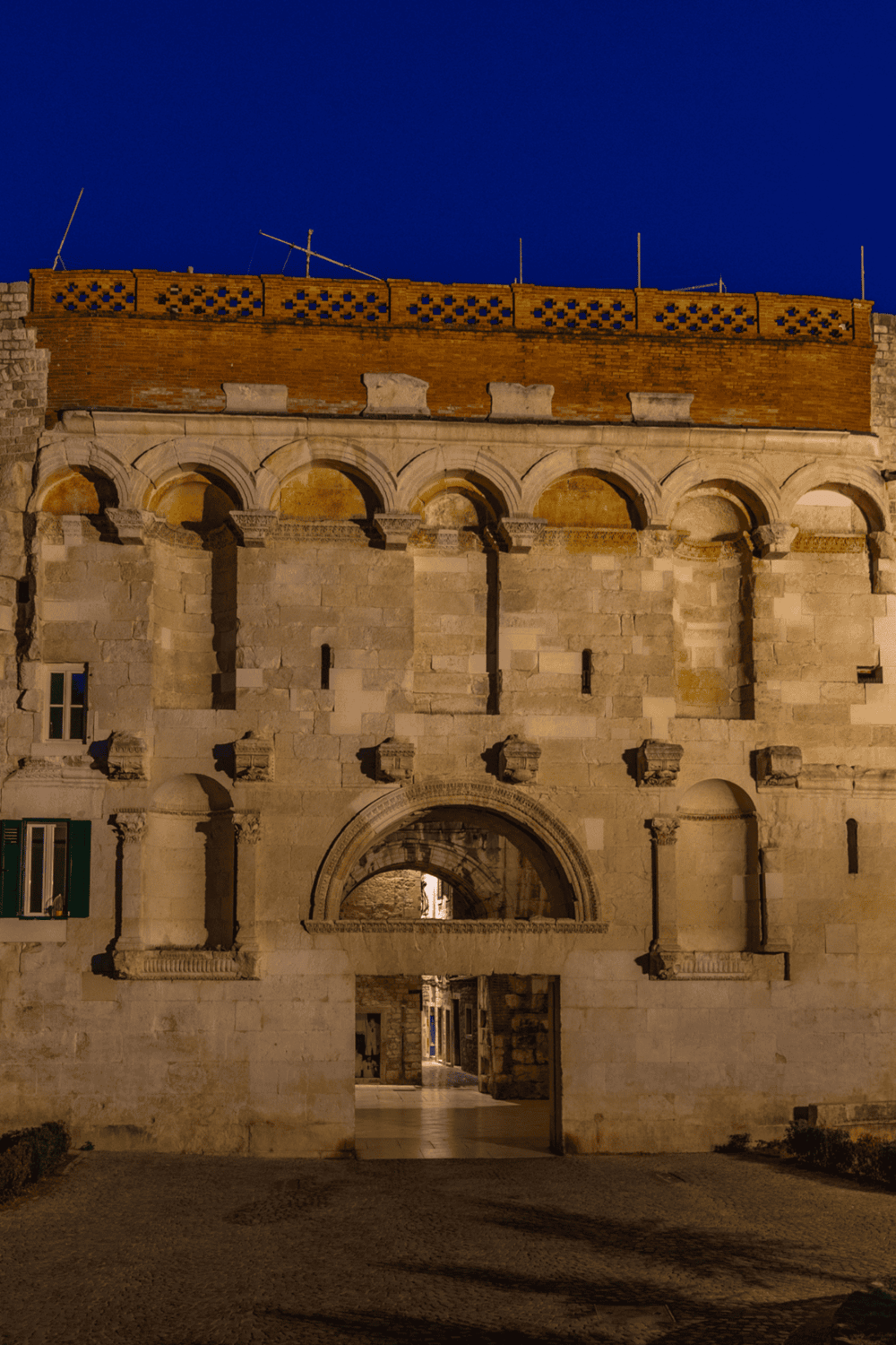 Ancient stone city gate lit at night, showcasing historical architecture and travel attractions.