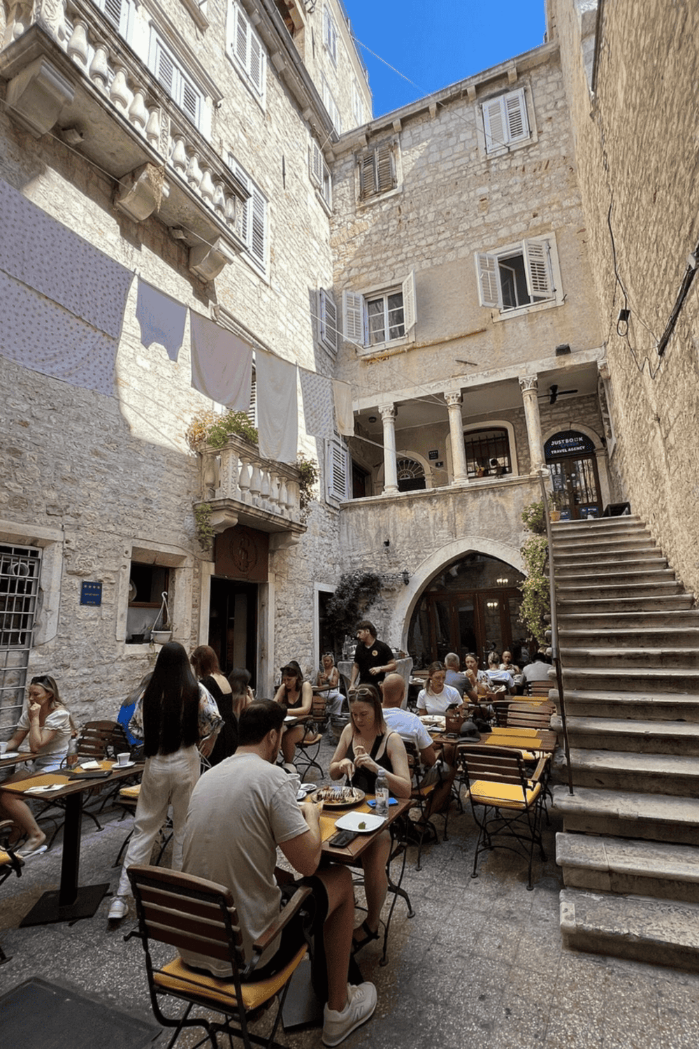 Outdoor dining in historic stone courtyard with authentic European atmosphere and vibrant street scene.