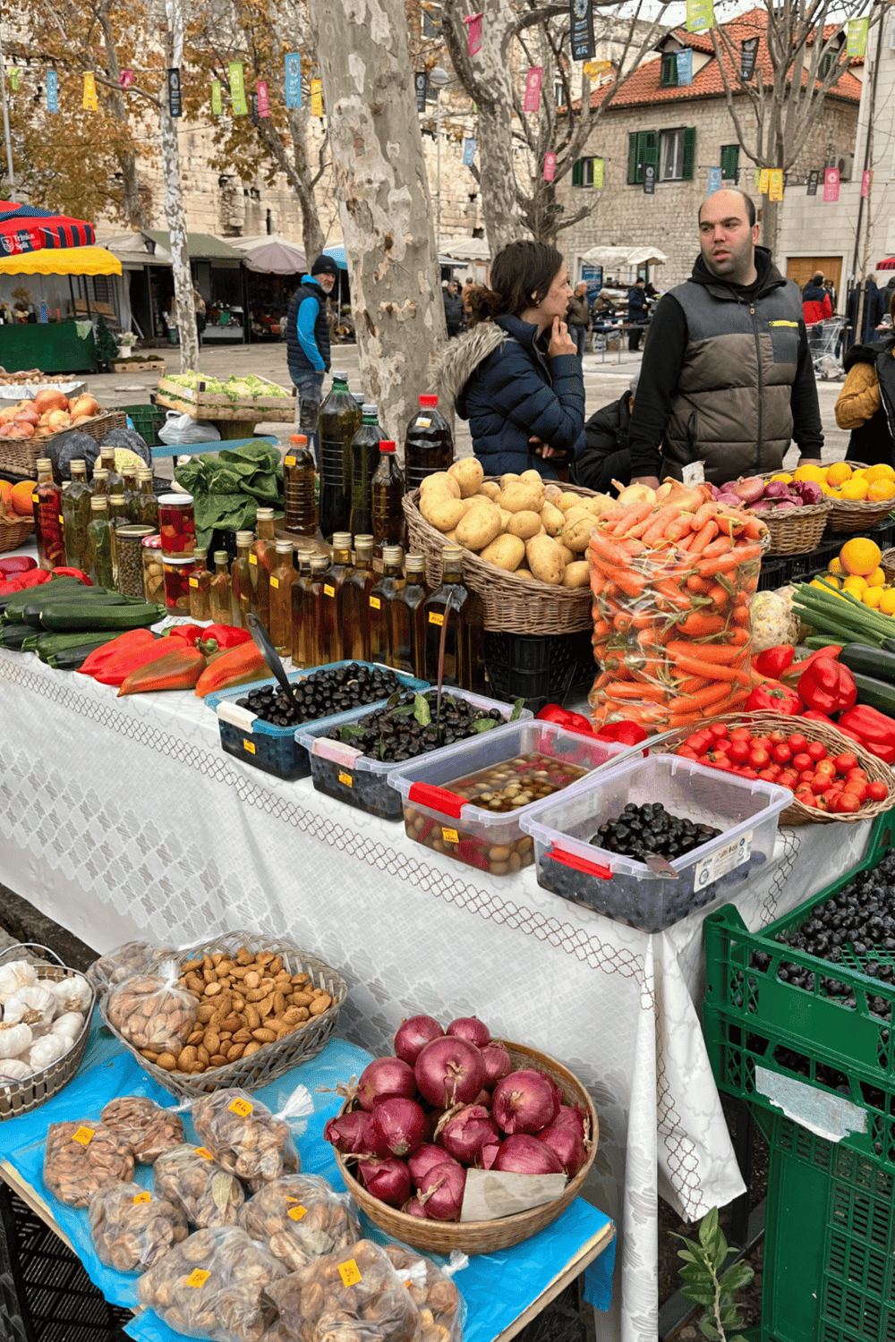 Fresh produce and local organic oils at outdoor market in Croatia, showcasing vibrant vegetables and regional products.