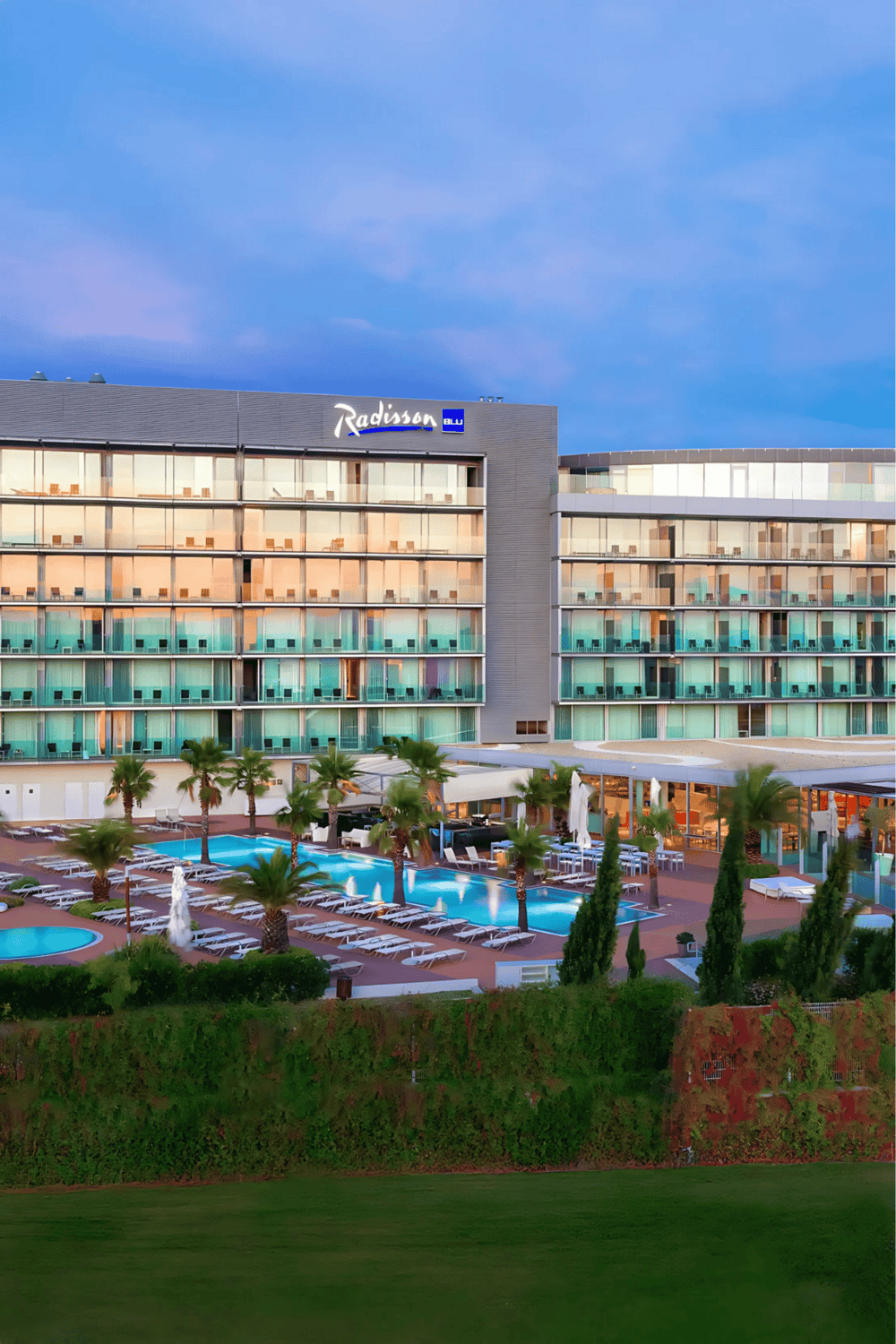 Elegant Radisson hotel with outdoor pool and lush greenery, perfect for leisure travel.