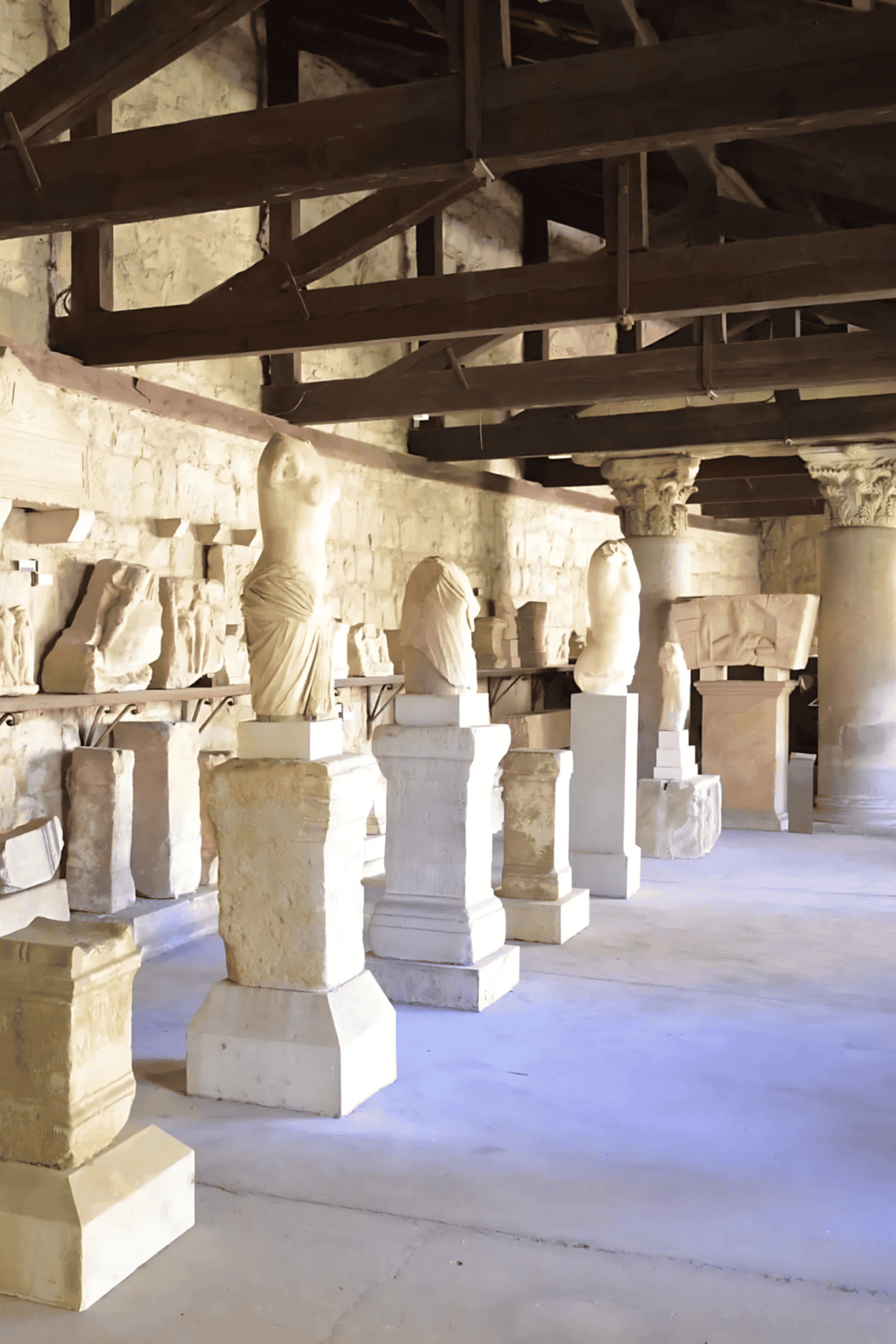 Ancient Greek marble sculptures and columns in a historic museum setting.