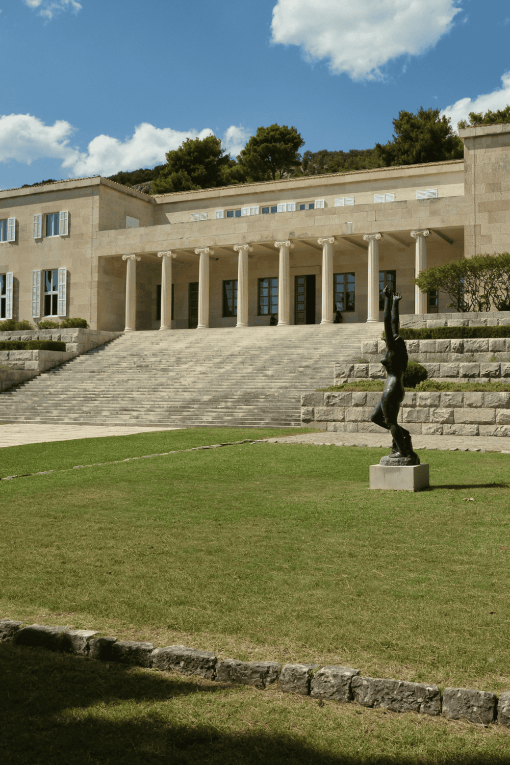 Ancient Greek-style building with columns and stairs on a sunny day.