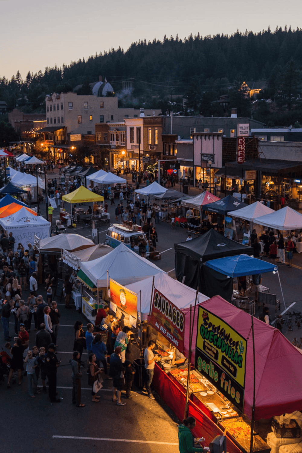 Biggest Street Market with food stalls and shoppers at dusk in a charming town.