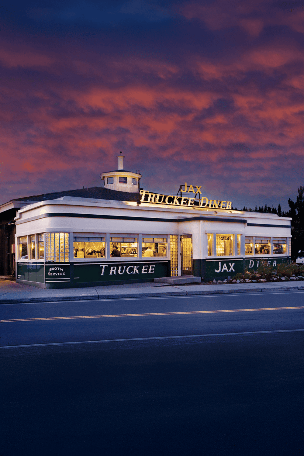 Vintage roadside diner at sunset with neon lights, classic American charm, and welcoming atmosphere.