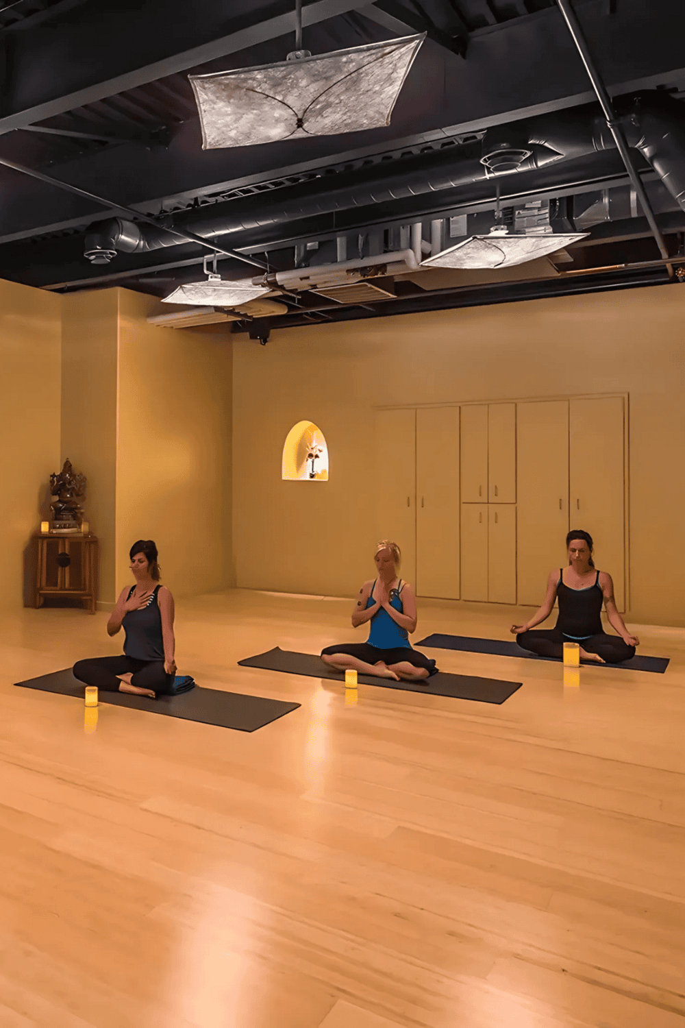 Calm yoga class in a peaceful studio with candles and natural lighting for relaxation and mindfulness.