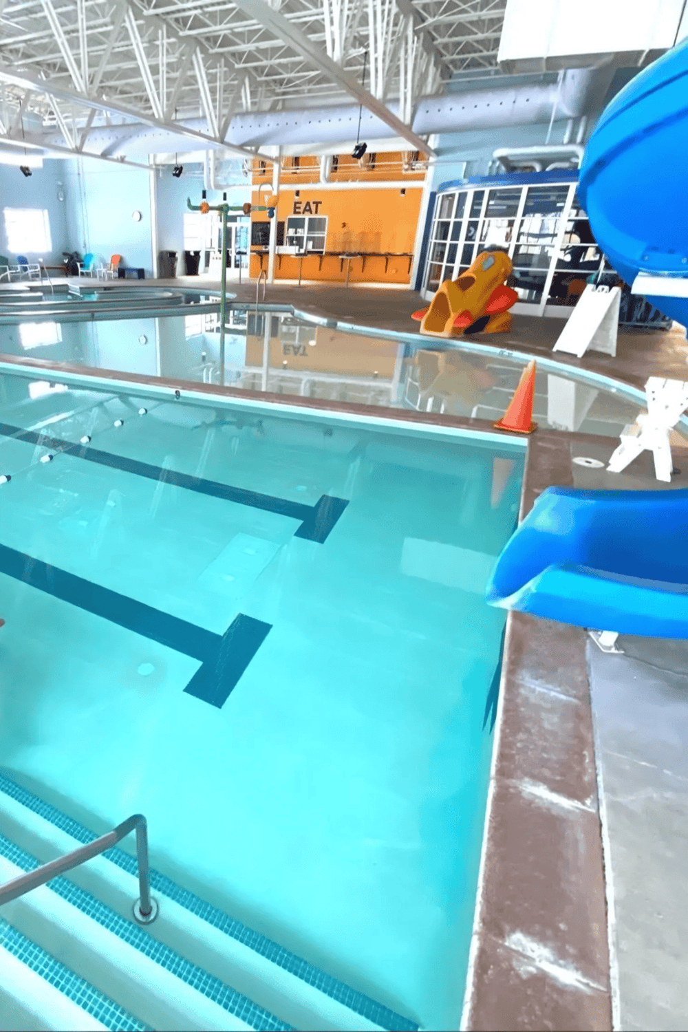 Indoor swimming pool area with water slide and play equipment at Quest For Directions facility.