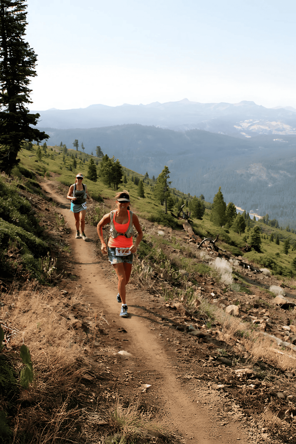 Hiking trail in mountainous landscape with women trail running in outdoor adventure, scenic nature, and healthy lifestyle.
