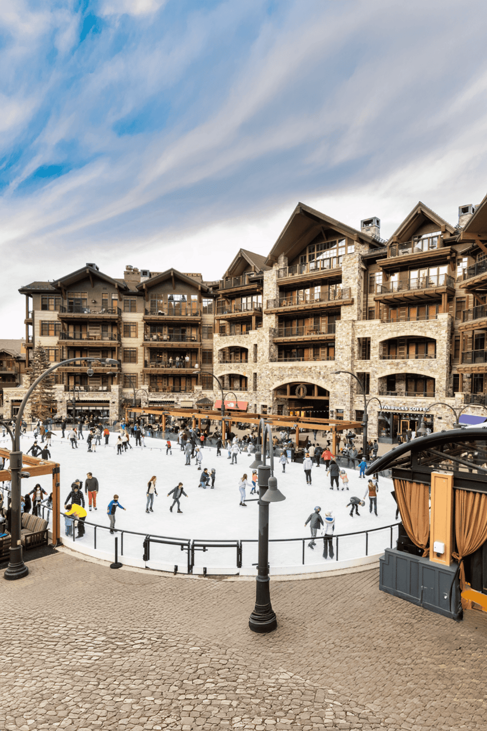 Cozy mountain lodge with outdoor ice skating rink in a winter resort setting.