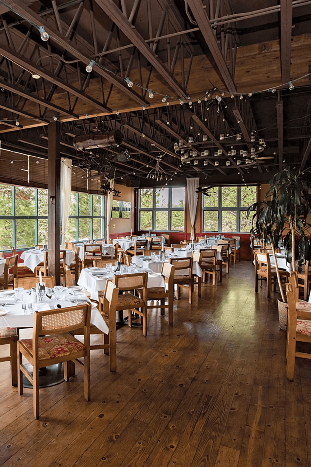 Elegant rustic restaurant with wooden accents, large windows, and cozy dining setup.