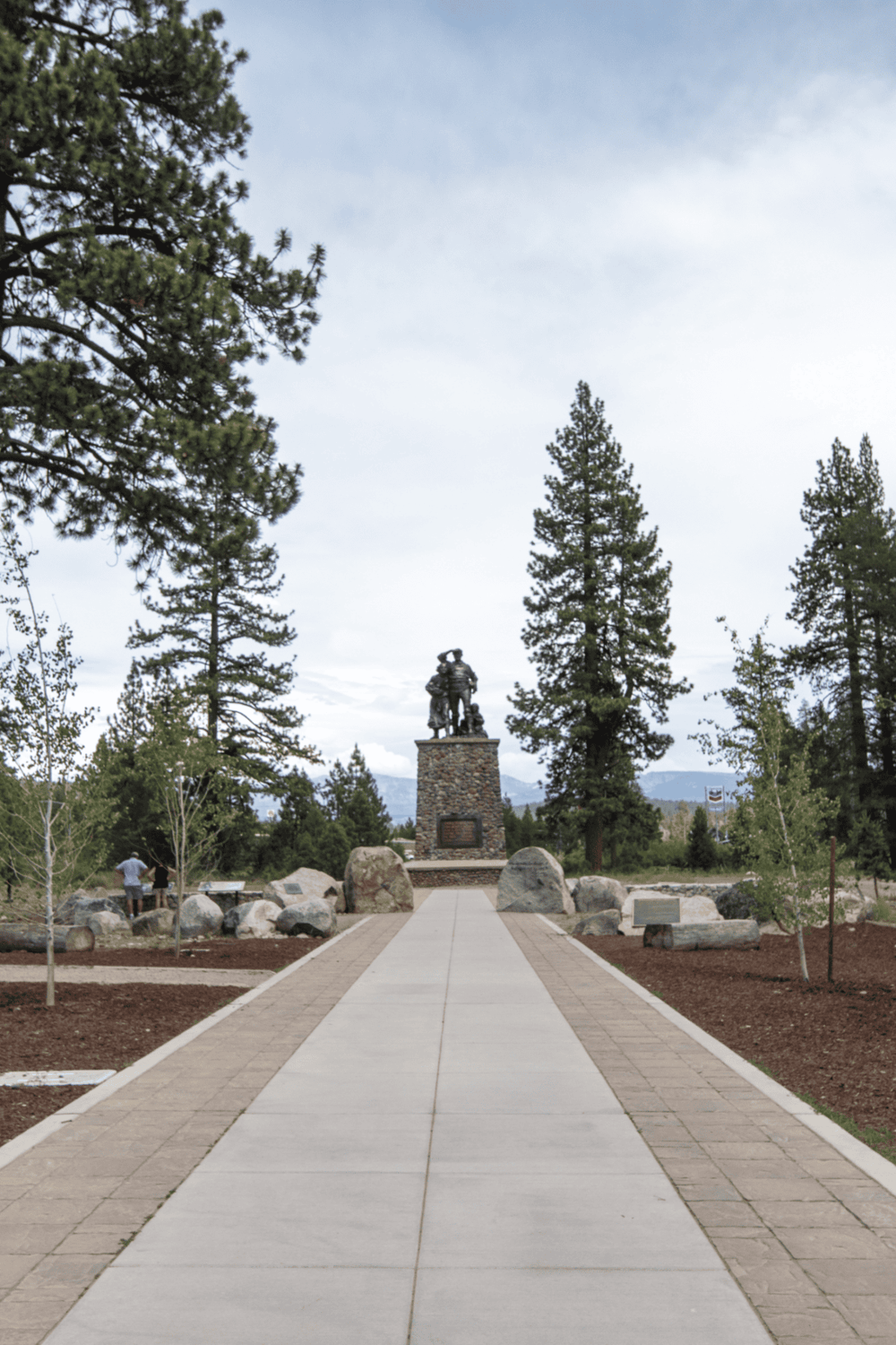 Historic military monument in a scenic park with tall pine trees and mountain backdrop.