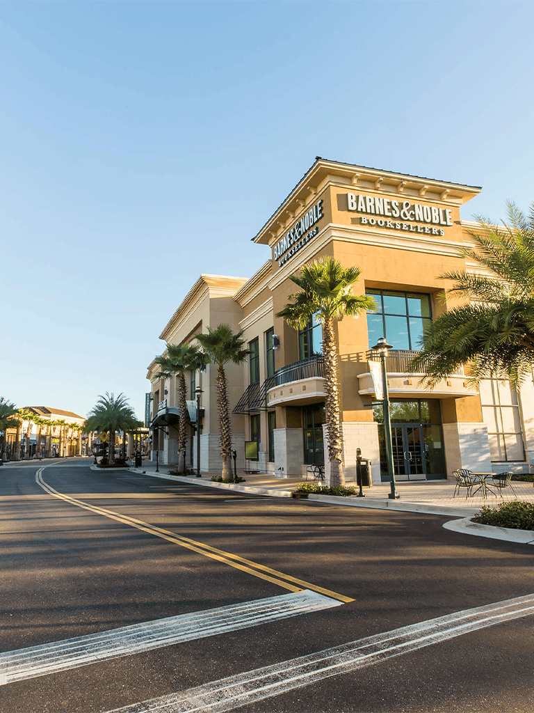 Upscale bookstore storefront with palm trees in a shopping district.