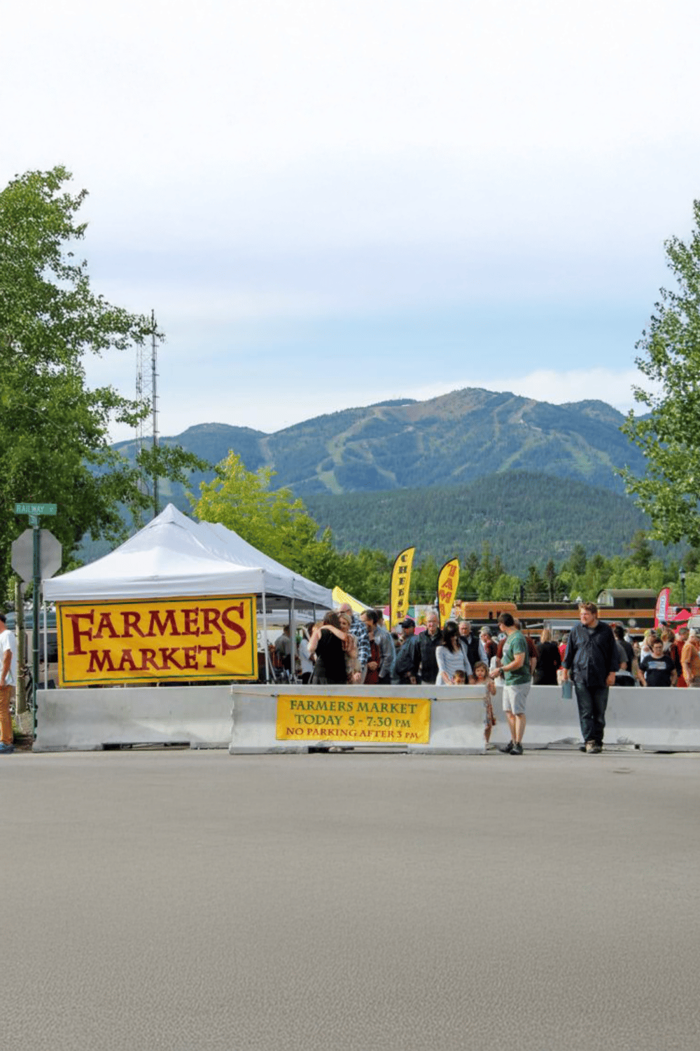 Farmers Market outdoor event with mountain scenery and crowds, showcasing local fresh produce.