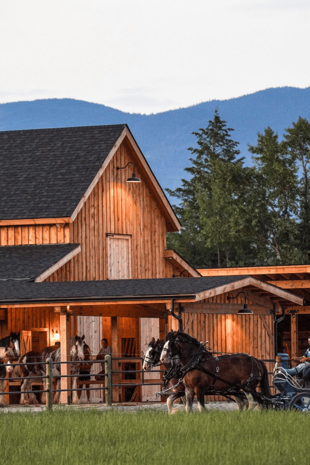 Tranquil farm scene with horse-drawn carriage outside rustic barn, scenic mountain background.