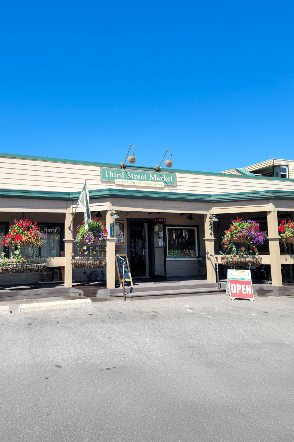 Charming storefront of Third Street Market with vibrant flowers, inviting entrance, and clear open sign.
