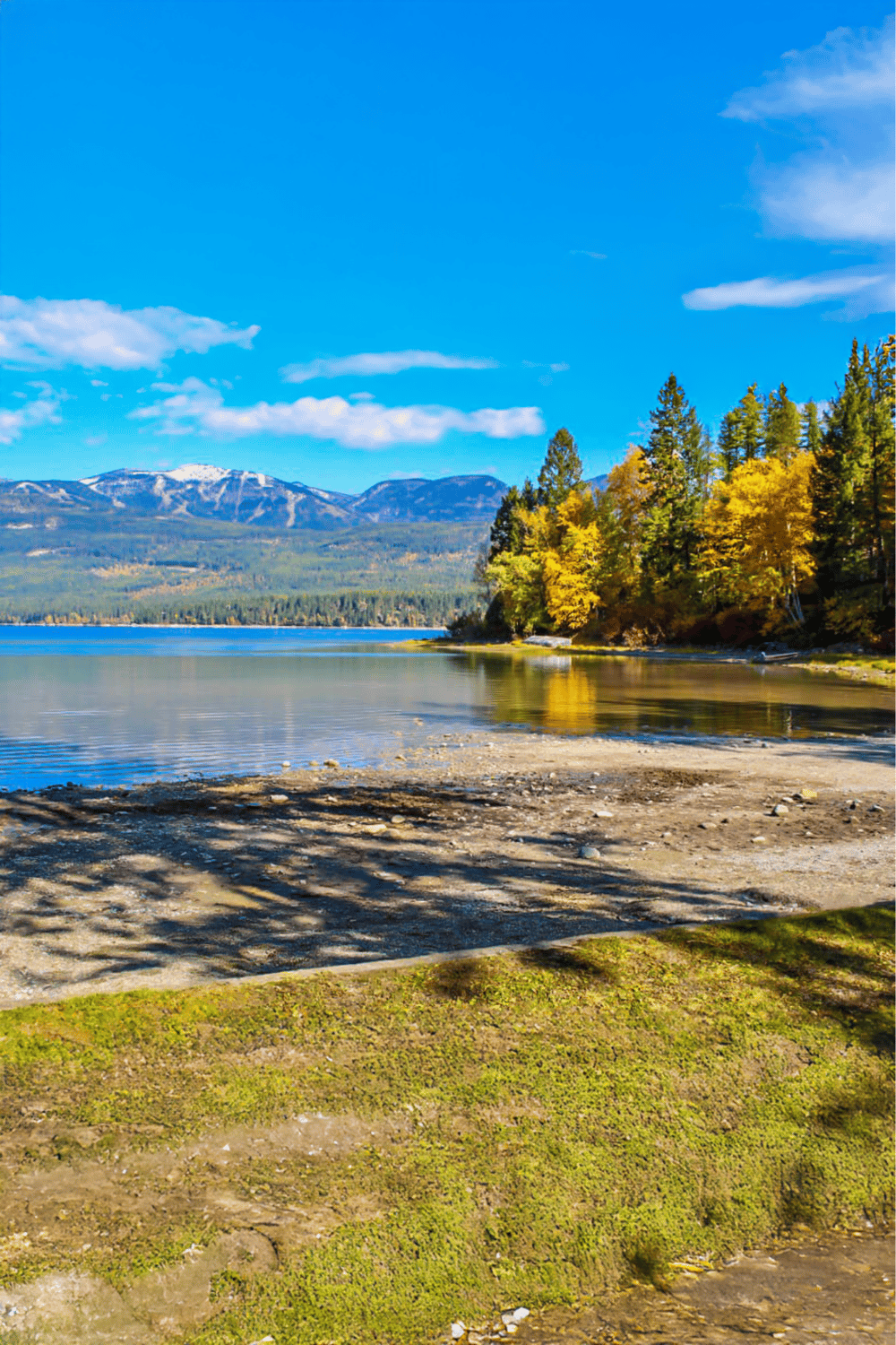 Pristine mountain lake with vibrant fall foliage and snow-capped peaks in the background.