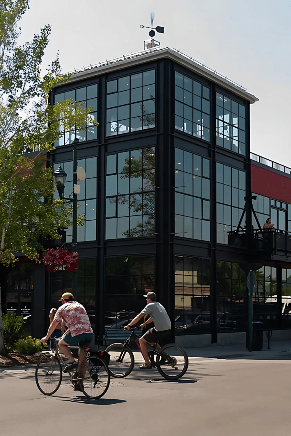 Modern commercial building with glass facade and people riding bikes nearby.