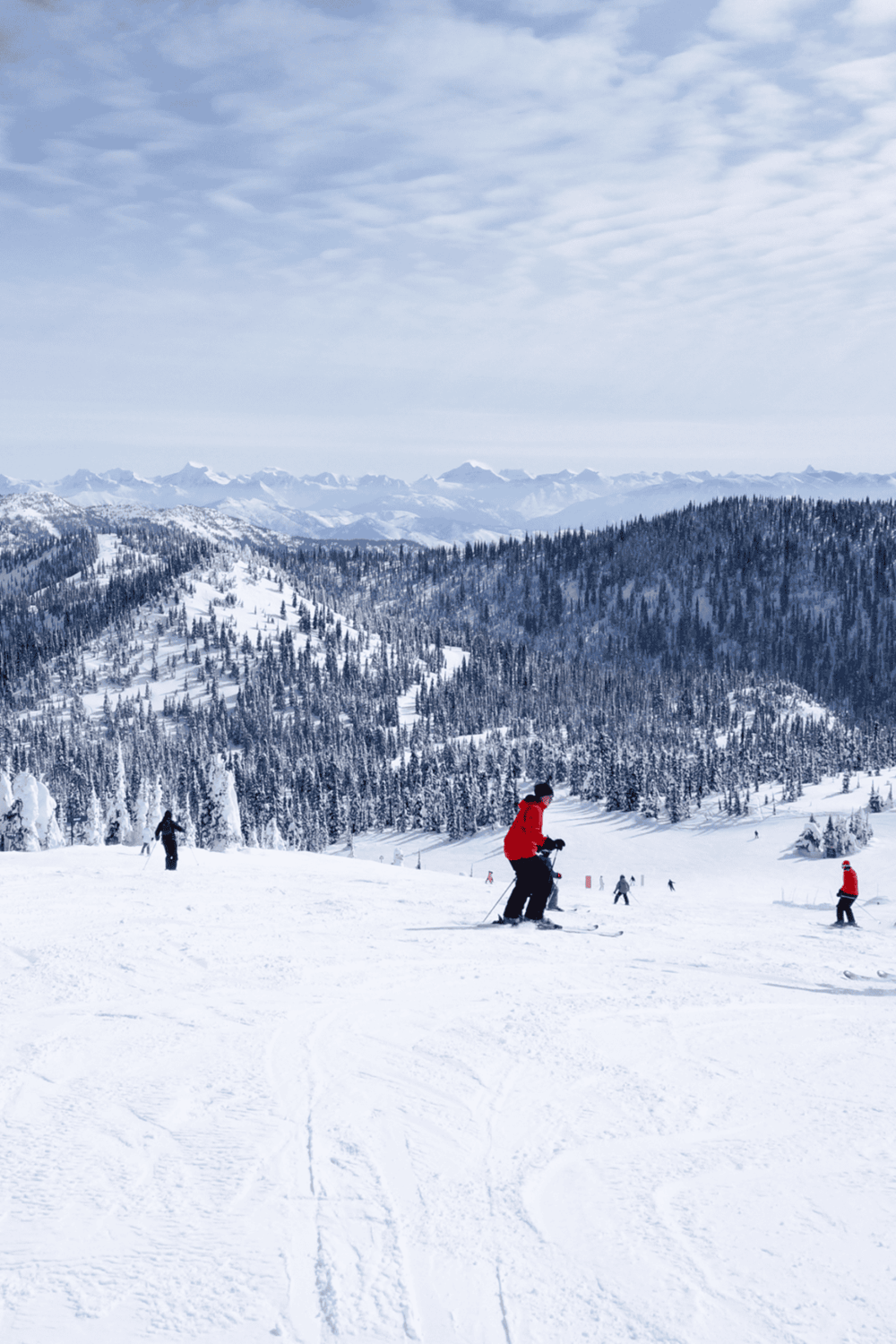Snowy mountain ski resort with skiers and panoramic alpine landscape in the background.