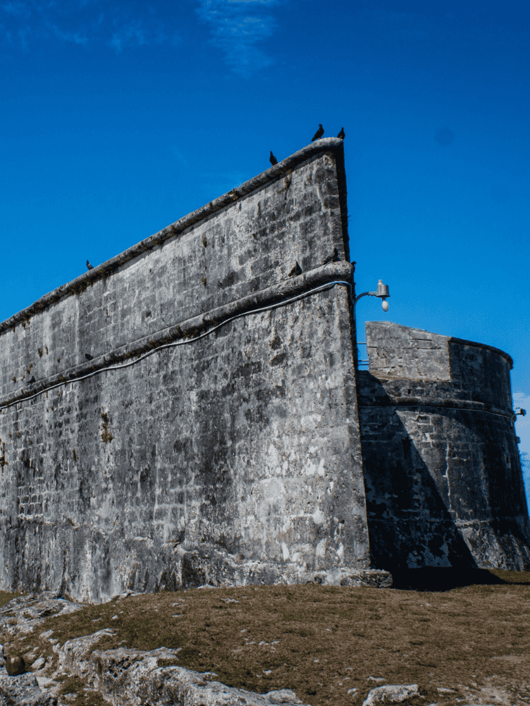 Ancient stone fortress with pigeon nests against blue sky, historical travel destination.