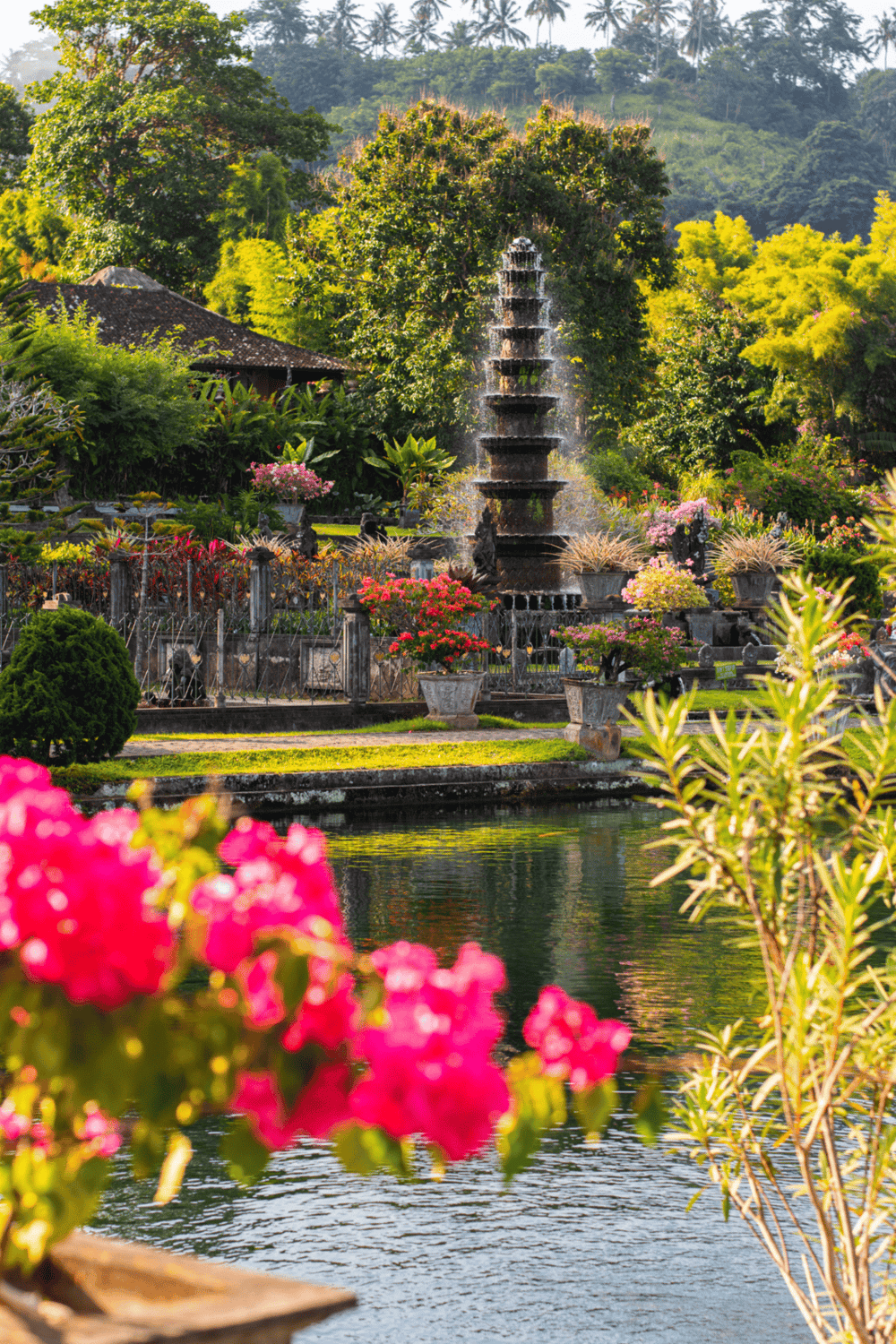 Tranquil garden with ornate fountain, lush greenery, colorful flowers, and peaceful pond in Bali.