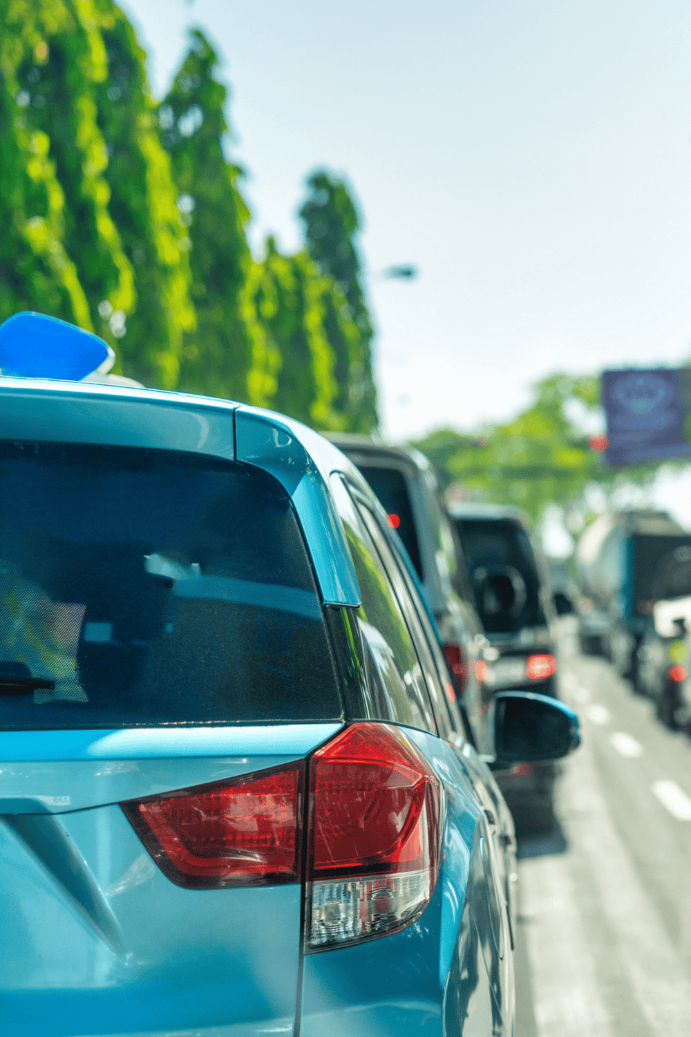 Blue car on busy road during daytime, traffic navigation, city driving, road trip.