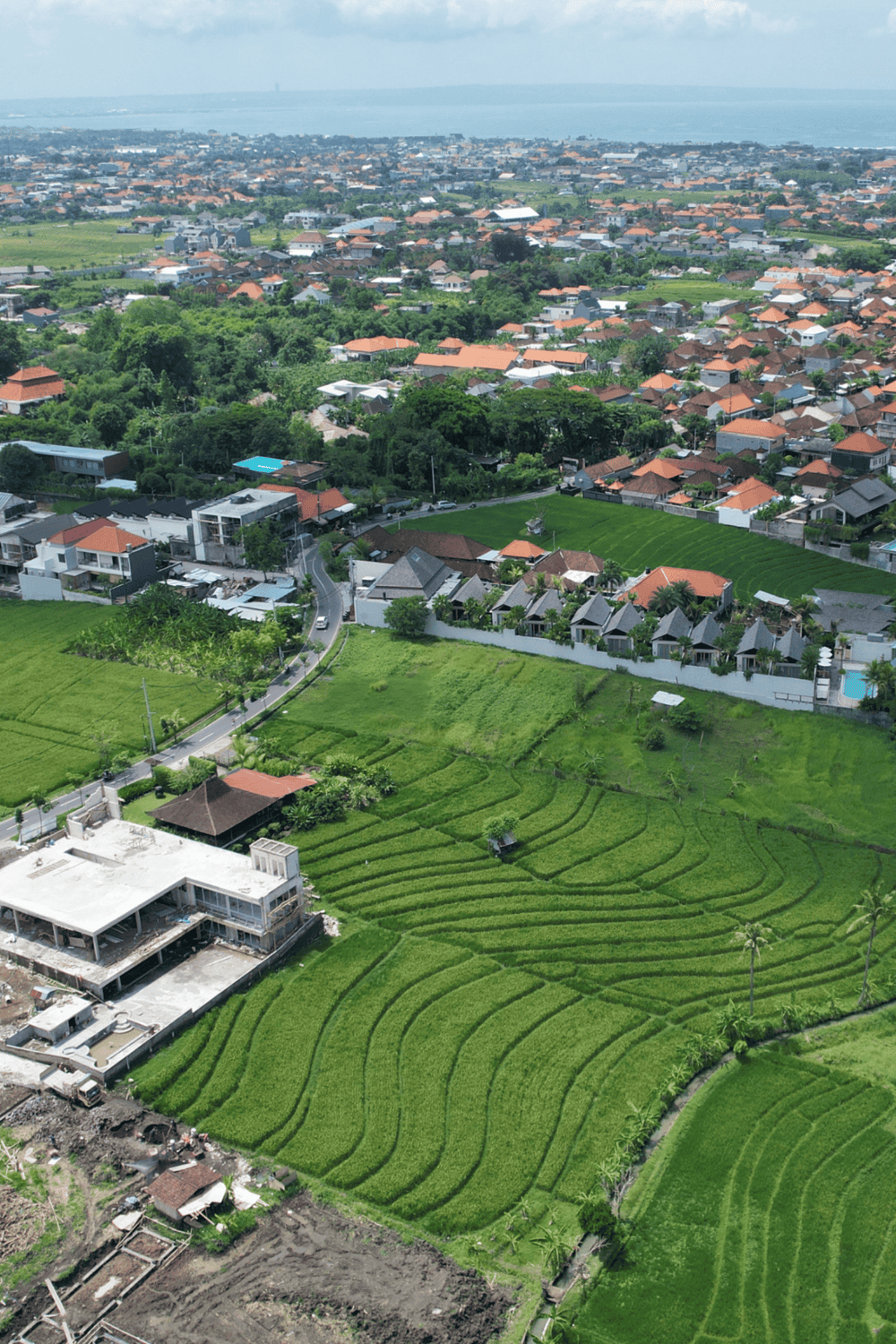 Vibrant aerial view of lush green rice terraces and residential neighborhoods in a scenic rural area.