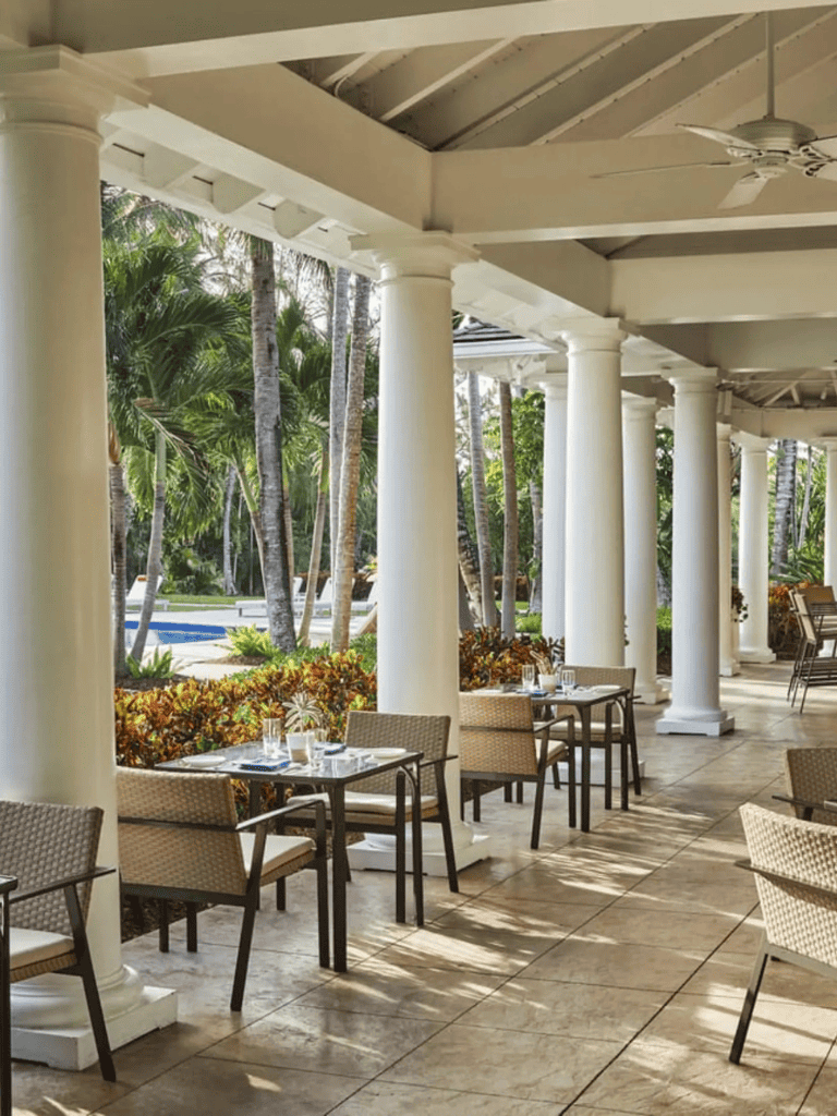 Elegant outdoor restaurant patio with white columns and tropical scenery for dining.
