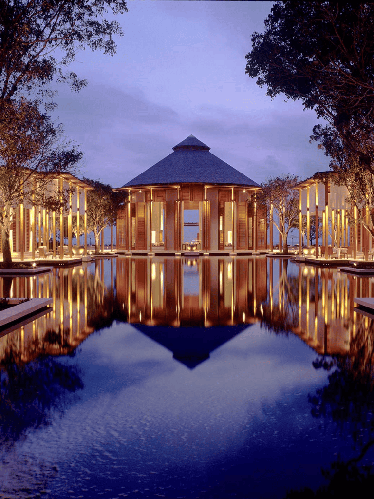 Elegant lakeside pavilion with warm lighting and surrounding trees at sunset.
