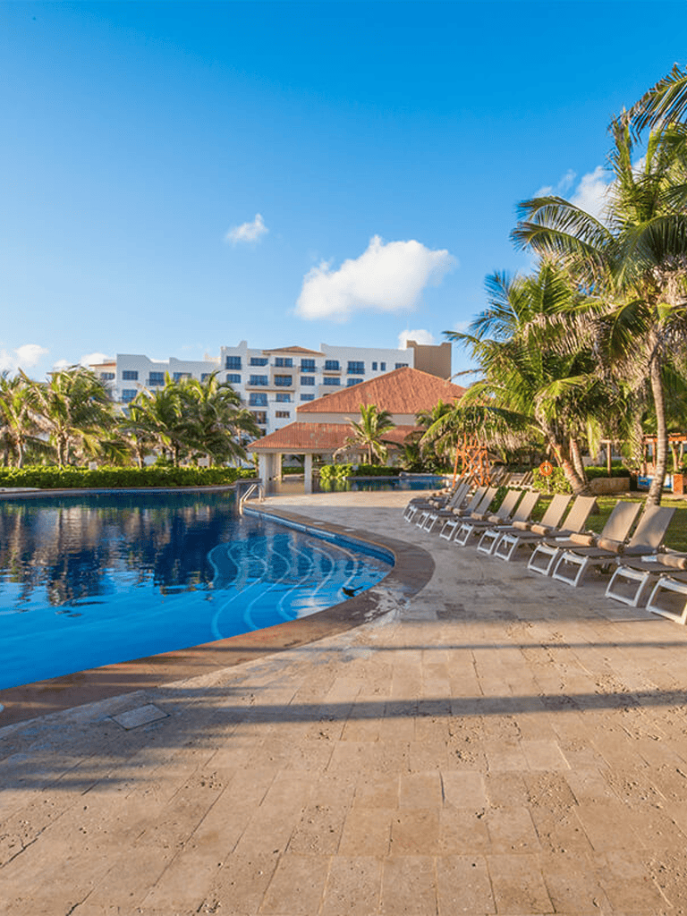 Luxurious resort pool with tropical palm trees and modern amenities for relaxation and vacation.
