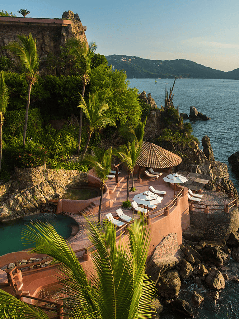 Serene coastal resort with pools, lush greenery, and ocean views, perfect for vacation relaxation.