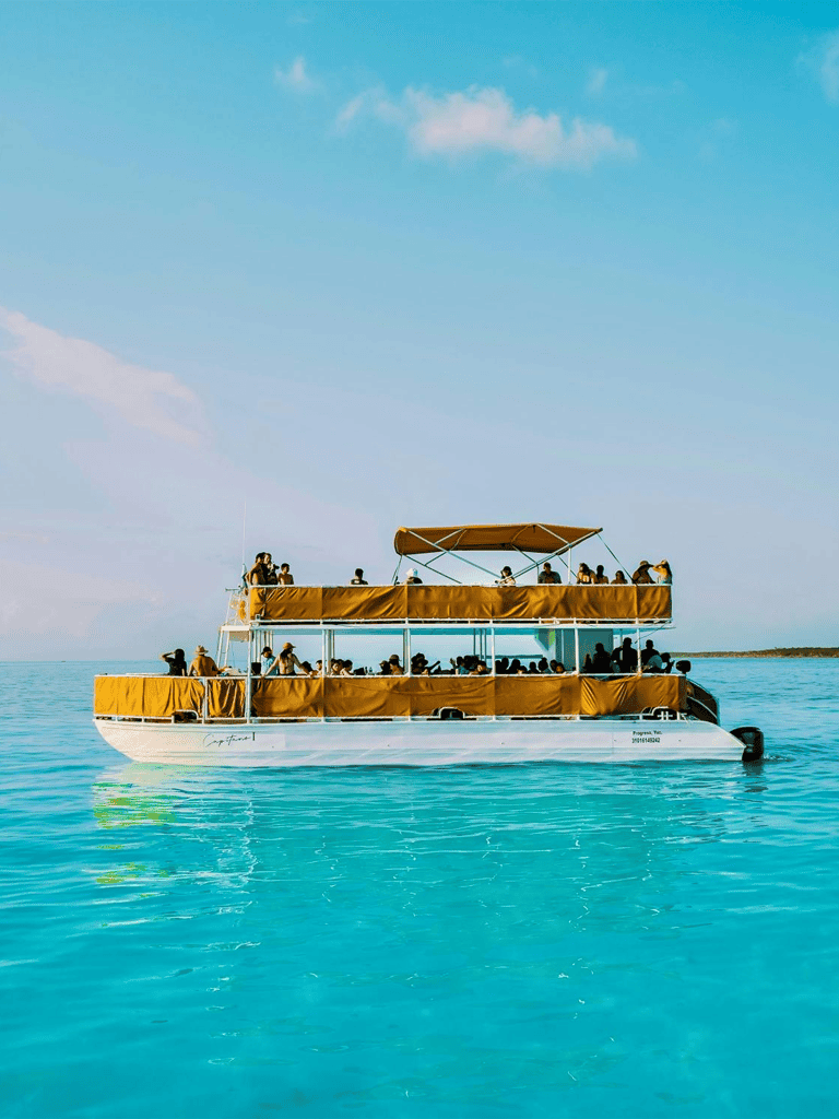 Relaxing boat tour with passengers on clear blue ocean water, sunny sky, and scenic coastal views.