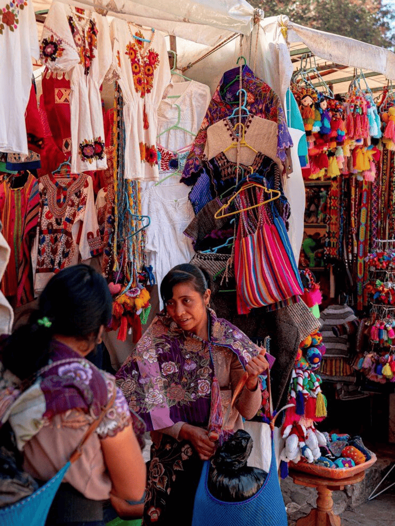 Colorful traditional clothing and handicrafts at a vibrant outdoor market stall.