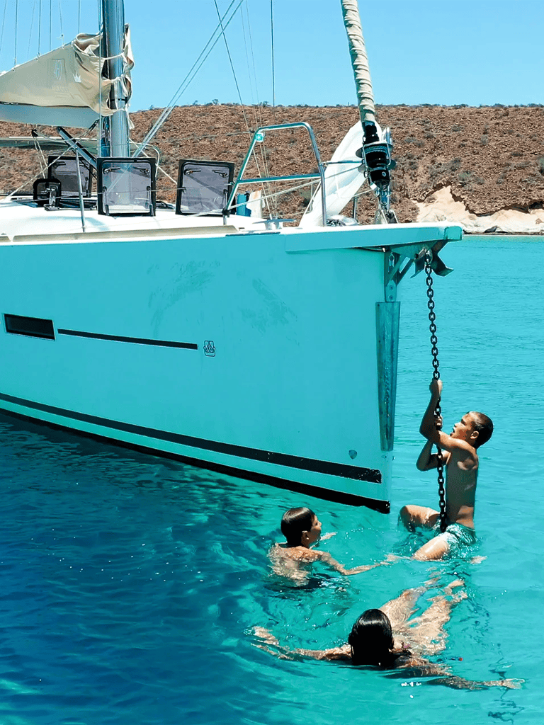 1. Kids swimming near a large sailing yacht at the marina.