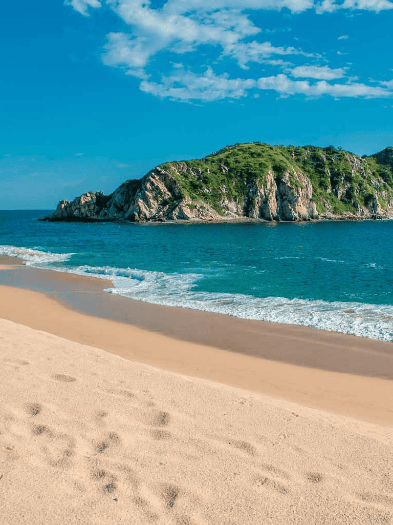 Tranquil beach with clear blue waters and green island, perfect for coastal exploration and relaxation.