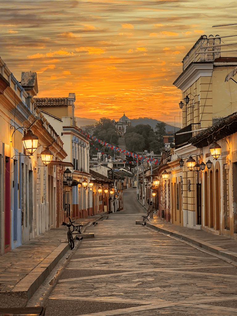 Colorful historic street in Antigua Guatemala at sunset, showing vibrant colonial buildings.