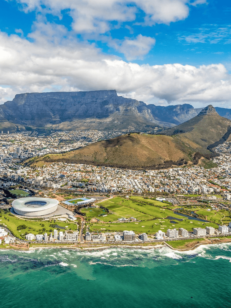 Aerial view of Cape Town with Table Mountain, stadium, and beachfront, showcasing South Africa's scenic cityscape and natural beauty.