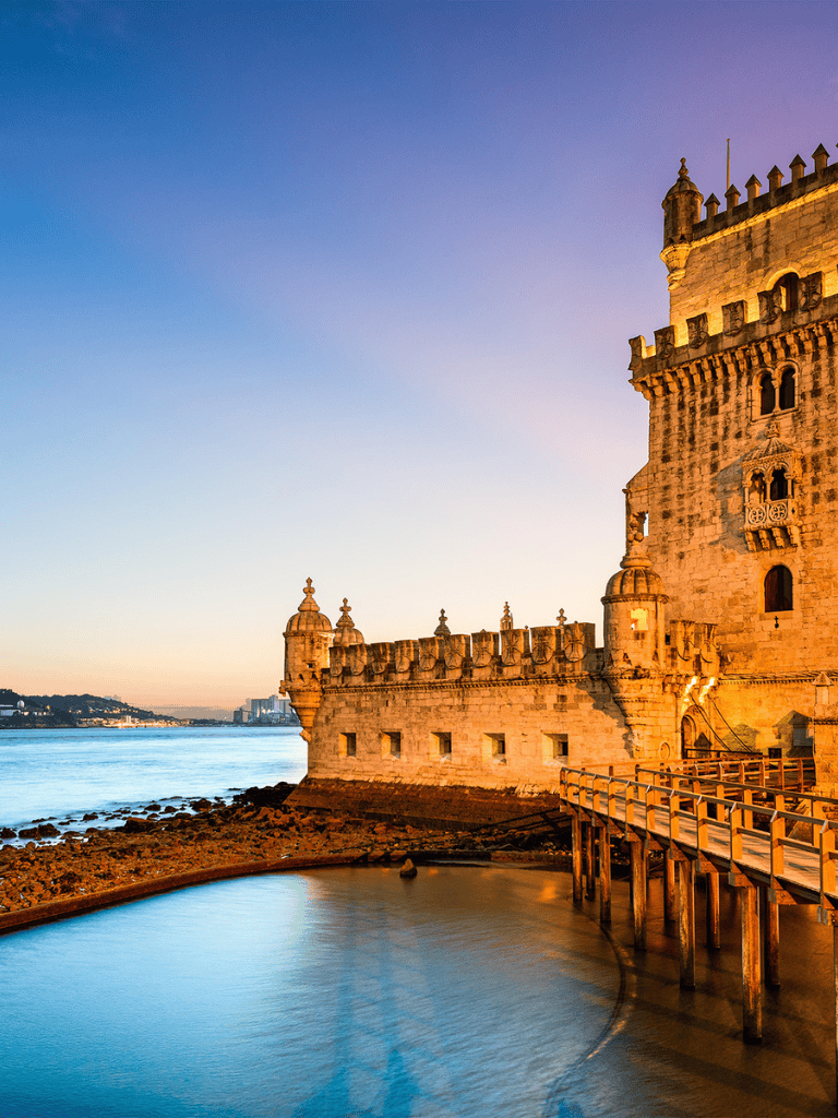 Majestic Lisbon castle along Tagus River at sunset with historic architecture and scenic views.