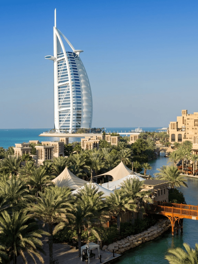 Luxury Dubai hotel with iconic sail-shaped tower and lush tropical gardens.