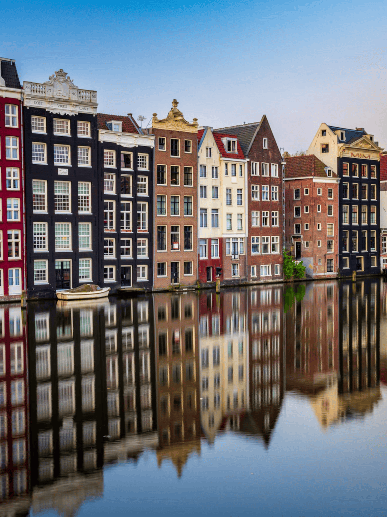 Colorful European canal houses reflecting in water, historic architecture, scenic cityscape, architecture photography, Amsterdam view.
