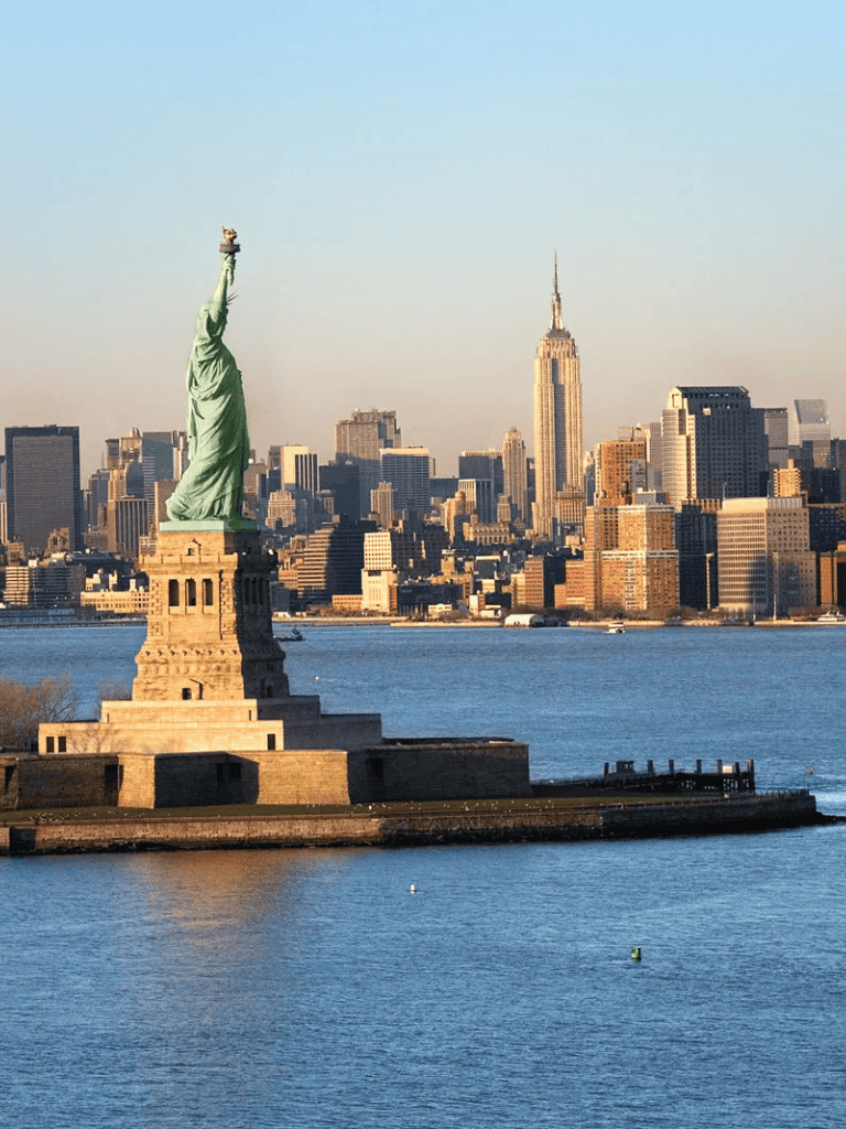 Large Statue of Liberty with NYC skyline in the background, featuring Empire State Building.
