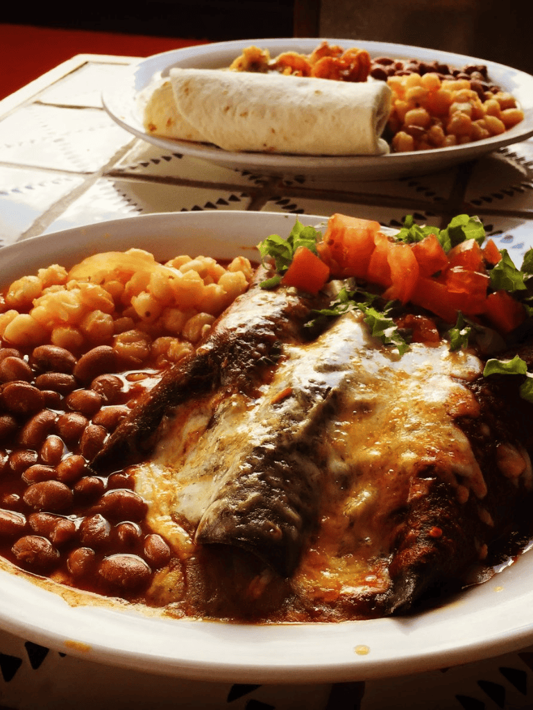 Steamed fish with beans, chickpeas, and fresh salad on a white plate.