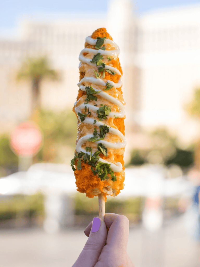 Crispy fried fish skewer with creamy sauce and herbs, perfect for tasty street food or outdoor eating.