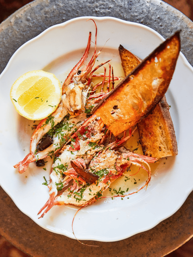 Succulent grilled prawns with lemon wedge and crispy bread slices, served for seafood dining experience.