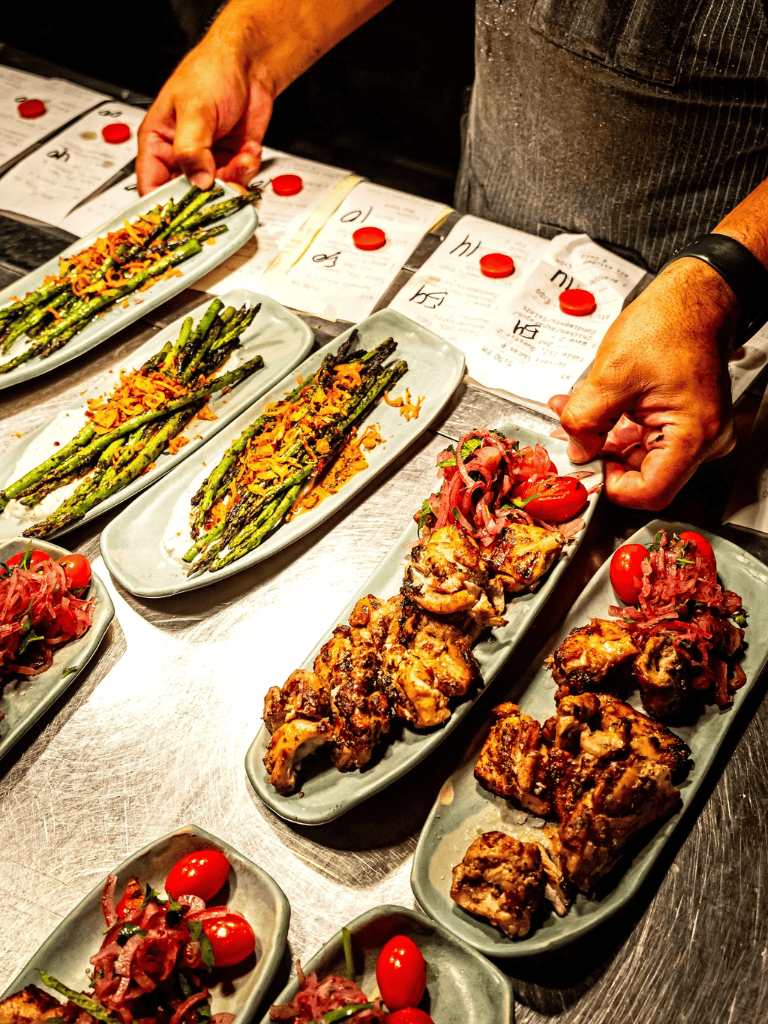 Grilled asparagus with herbs and roasted cherry tomatoes on plates, ready for serving at a restaurant.