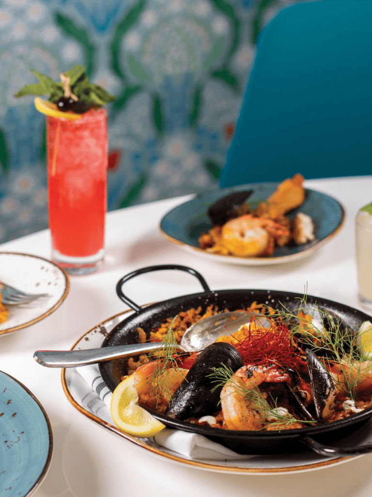 Seafood paella with shrimp, mussels, and herbs on a dining table.