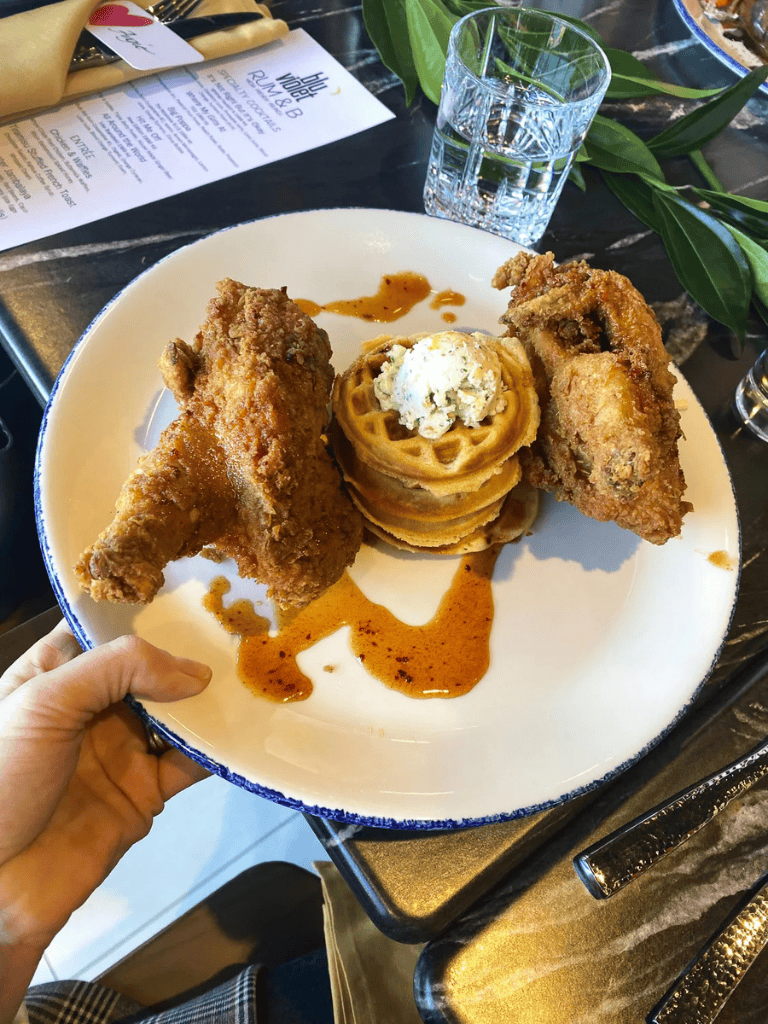 Crispy fried chicken wings with waffles and butter cream on a white plate, served with barbecue sauce.
